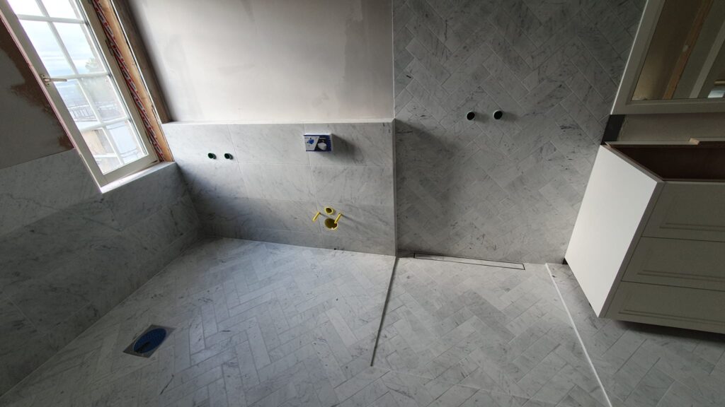 Strefa prysznica walk-in z odpływem liniowym i marmurową podłogą